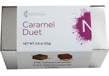 Load image into Gallery viewer, 2 dimensional silver rectangle box with a label wrapped around the box stating, “Caramel Duet” with NeoCocoa logo and net weight  0.8 oz (23g). Can see a little of the side of the label with image of one dark salted caramel truffle and one milk salted caramel truffle.