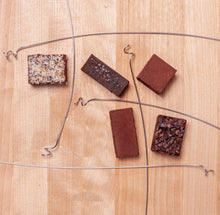 Load image into Gallery viewer, Artistic view of the 5 truffles laid out on wood with curled wire dividing them from each other.