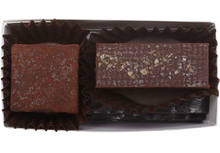 Load image into Gallery viewer, Above view and inside the rectangle box, one cube shaped Zested Lime truffle (coated in cocoa powder) and one rectangle shaped almond butter truffle with a few flakes of salt. Each truffle is in a brown paper candy cup.