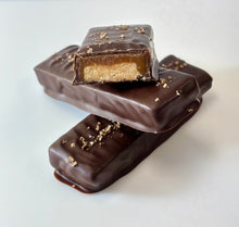 Load image into Gallery viewer, 3 chocolate caramel bars stacked, 1 bar sliced to view the center of shortbread caramel and chocolate, topped with sea salt crystals