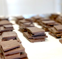 Load image into Gallery viewer, Stacks of broken smoky mocha brittle on a sheet pan showing thin layers of toffee and chocolate