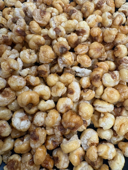 A close-up view of caramelized popcorn kernels piled together, showing golden-brown and cream tones with some darker toasted areas.