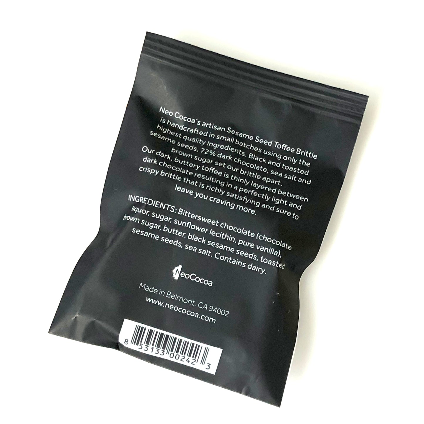 Back side of Sesame brittle 1oz sized bag with description of product, ingredients, bar code and logo.