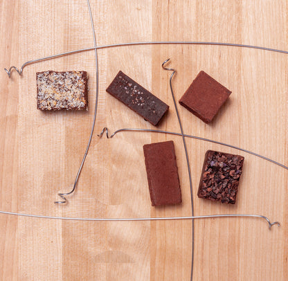 Artistic view of the 5 truffles laid out on wood with curled wire dividing them from each other.