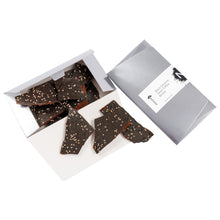 Load image into Gallery viewer, 2 dimensional angle of opened 8oz box with title of “Black Sesame Seed Toffee Brittle” with NeoCocoa logo and 8oz pile candy pieces inside the box bottom. 3 pieces of candy spilling out.