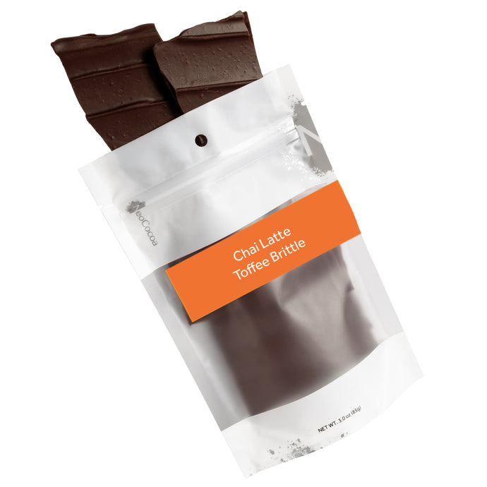 Chai Latte brittle pouring out of 3oz sized bag with orange label stating “Chai Latte Toffee Brittle” and NeoCocoa logo.