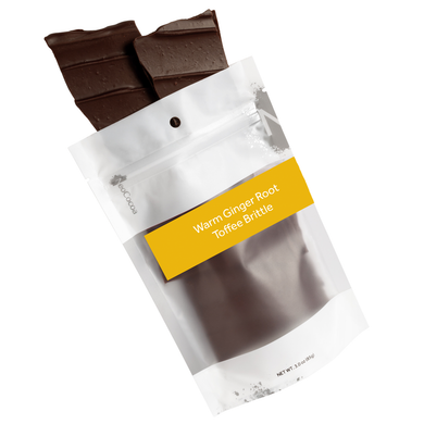 Warm ginger root brittle pouring out of 3oz sized bag with label stating “Warm Ginger Root Toffee Brittle” and NeoCocoa logo.