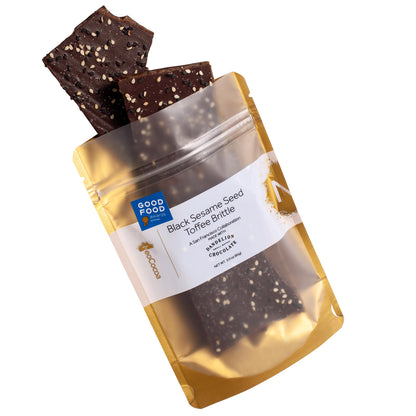 Sesame brittle pouring out of 3oz sized gold bag with label stating “Black Sesame Seed Toffee Brittle” collaboration with Dandelion Chocolate and NeoCocoa logo, with Good Food Award sticker.