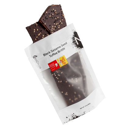 Sesame brittle pouring out of 3oz sized white bag stating “Black Sesame Seed Toffee Brittle” and NeoCocoa logo, with a Good Food Award sticker and a SOFI Gold award sticker.