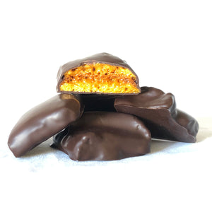 A 3oz pile of chocolate covered honeycomb candy pieces with one piece broken open to expose honeycomb candy inside.