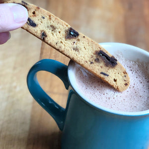 1 sesame brittle biscotti being dunked in a mug of hot chocolate.